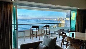 Una sala de estar moderna con un balcón que da a una vista panorámica de la ciudad y el mar.