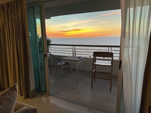 Ein Balkon mit Tisch und Stühlen, Blick auf das Meer und ein Vorhang.