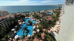 Un resort con piscina, palmeras y vista al océano.