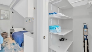 A compact bedroom with a bed, a small desk, a white wardrobe with shelves, and a bedside table. - 1 Bedroom Studio in Waterfront Building with Dock Access (Treasure Island)