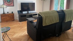 A living room with a sofa, a TV, a lamp, a small table, and a picture on the wall. - Gorgeous One Bedroom Flat in Woolwich Arsenal (London)