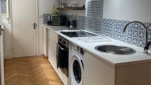 A compact kitchen with a washing machine, a sink, and a built-in oven. - Gorgeous One Bedroom Flat in Woolwich Arsenal (London)