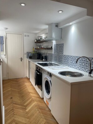 A compact kitchen with a washing machine, a sink, and a built-in oven. - Gorgeous One Bedroom Flat in Woolwich Arsenal (London)