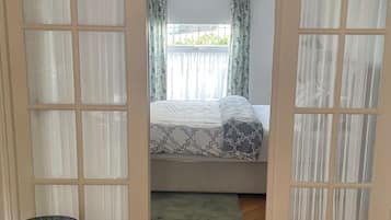 A room with a bed, a small table, and a herringbone-patterned floor.