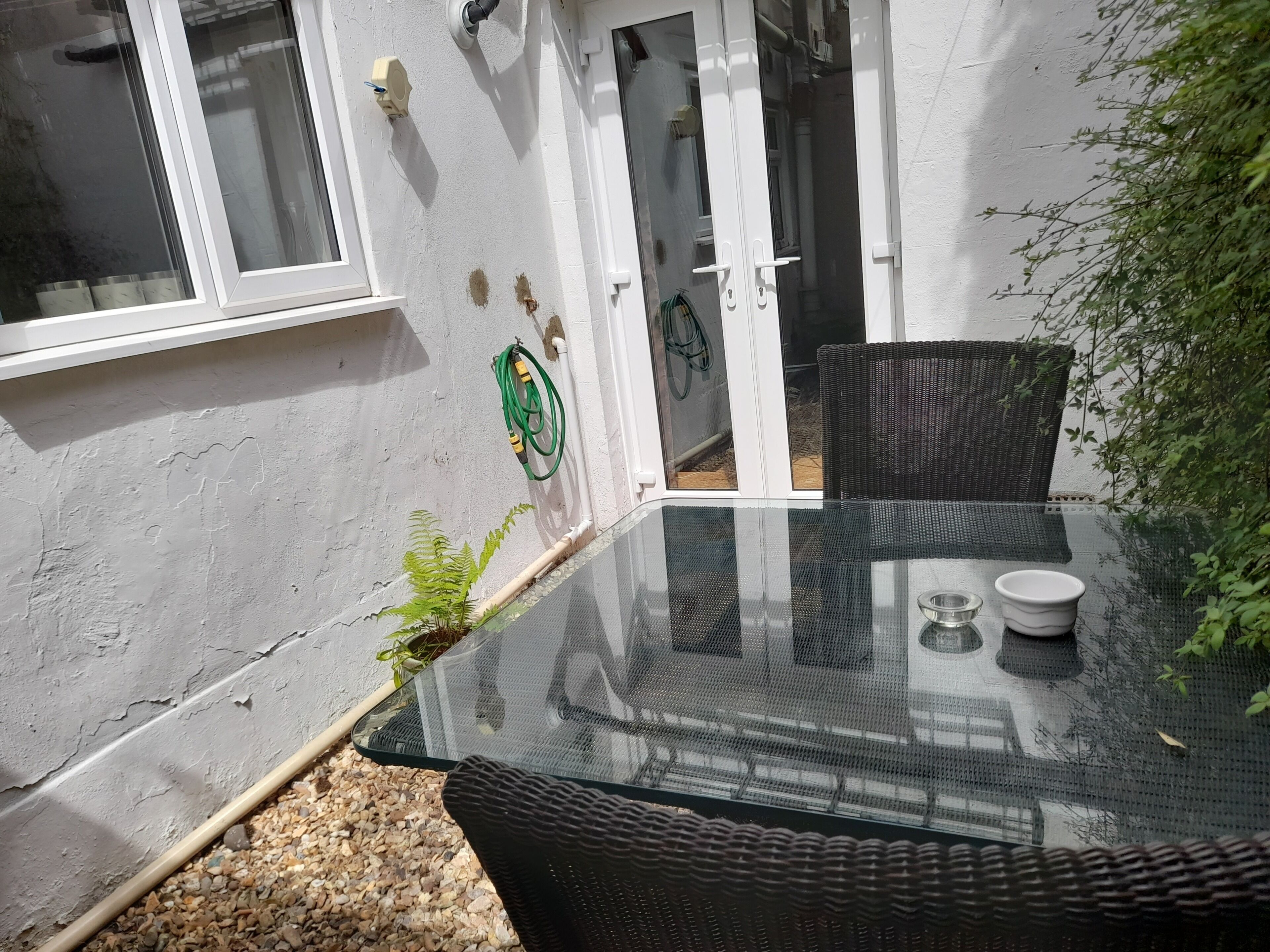 A glass-top table with two chairs, a small potted plant, and a white bowl.