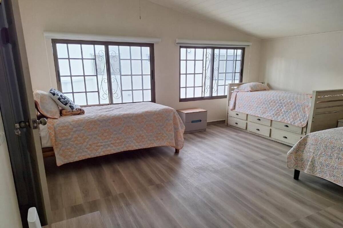 A bedroom with two beds, a dresser, and a window.