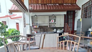 Una mesa de comedor de madera con sillas, una cocina con armarios y electrodomésticos, y vistas a un jardín.