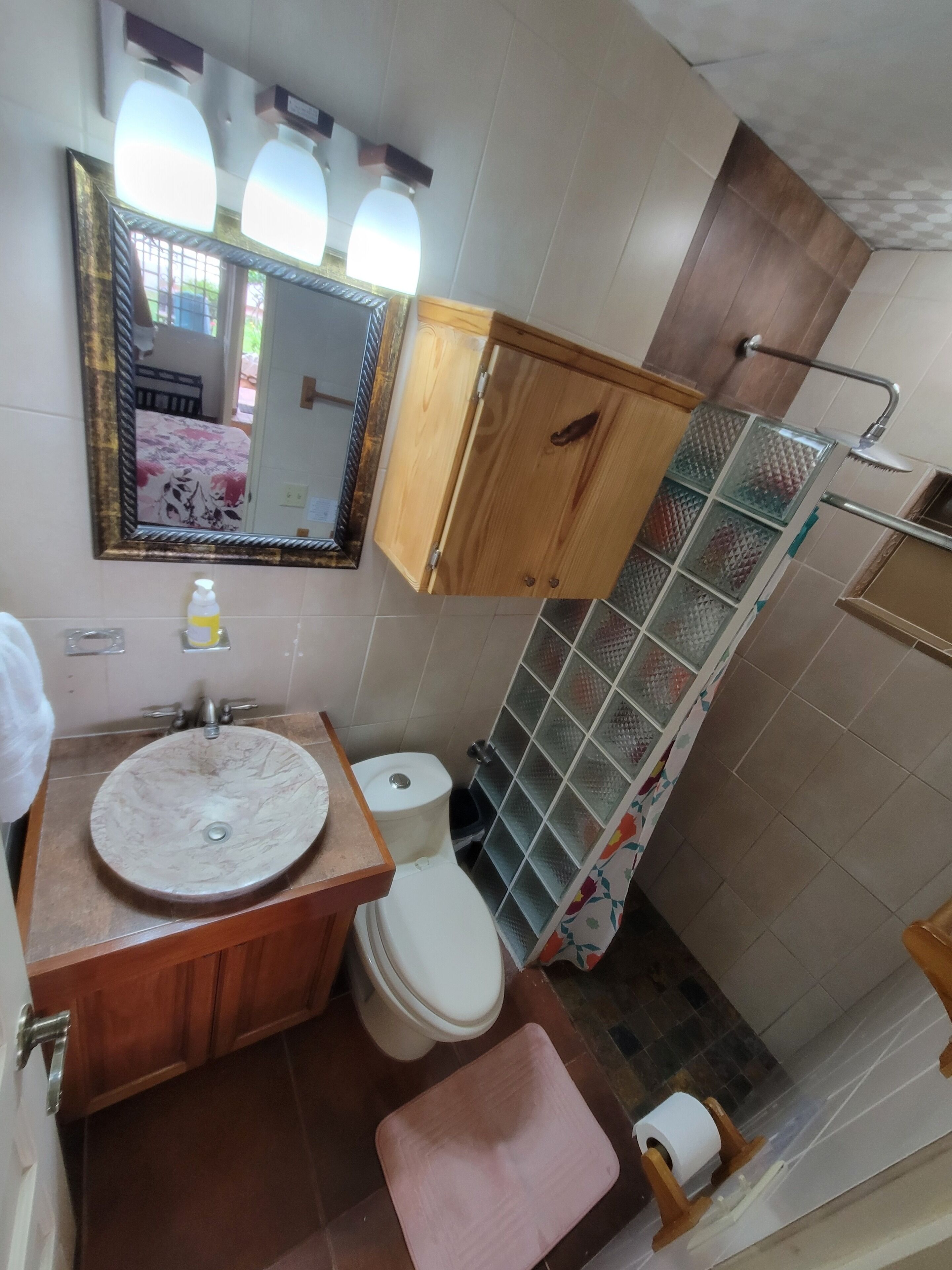 A bathroom with a wooden vanity, a sink, a toilet, a mirror, and a shower with a glass door.