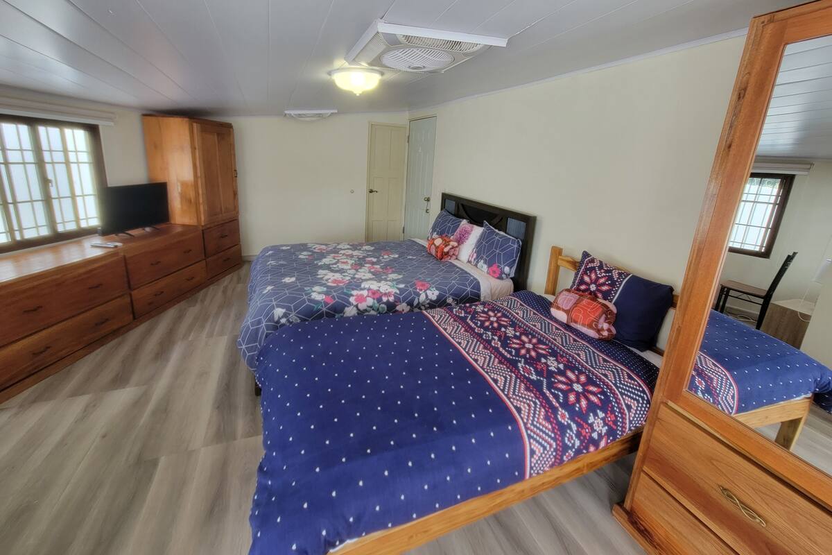 A bedroom with a bed, dresser, and a television on a wooden cabinet.