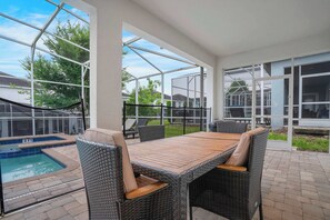 A covered patio with a pool, wicker furniture, and a view of neighboring houses. - 8BR family retreat w/ game room & pool (Four Corners)
