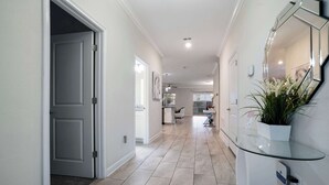 A hallway with a glass-top table, a potted plant, and a door leading to another room. - 8BR family retreat w/ game room & pool (Four Corners)