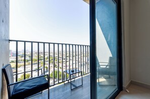 Een balkon met uitzicht op een stadsgezicht, een tafel en een stoel.