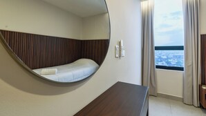 Una habitación con una cama redonda, cabecero de madera, vistas a la ciudad y una ventana con cortinas.