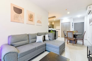 A modern living room with a grey sectional sofa, a dining table with chairs, and artwork on the walls. - Arena Vive (Monterrey)