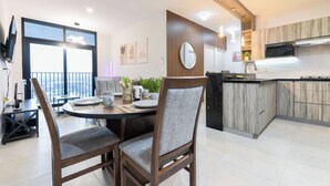 Una cocina moderna con comedor, muebles de madera y un ventanal grande.