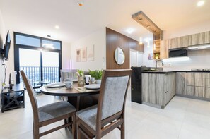 Een moderne keuken met een eethoek, houten kastjes en een groot raam.