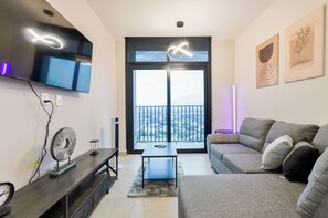 Een moderne woonkamer met een flatscreen televisie, een bank, een salontafel en een balkon met uitzicht.