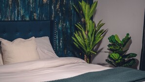 Un letto con lenzuola bianche, una testiera blu e una coperta verde.