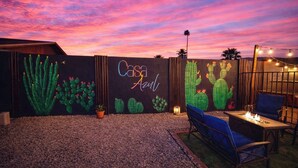 Un'area patio esterna con un murale che raffigura cactus e il testo 'Casa Aida'.
