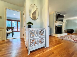 A room with a fireplace, a mirror, and a wooden floor.