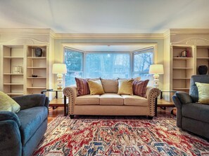 A living room with a beige sofa, patterned rug, and two armchairs.