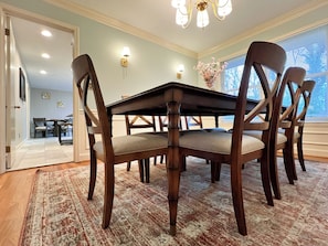 A dining room with a dark wooden table and chairs, a patterned rug, and a chandelier.