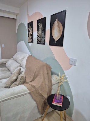 Um quarto com uma cama, uma mesa de cabeceira com livros e obras de arte na parede.