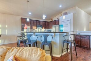 A modern kitchen with dark wooden cabinets, a central island with bar stools, and pendant lighting. - Cozy Colorado Escape w/ Grill, Hot Tub, & Mountain Views. (Berthoud)