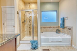 Un baño con cabina de ducha de vidrio, bañera, ventana y perchero para toallas.