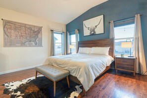 A bedroom with a large bed, a wooden bench, a map on the wall, and a window with curtains. - Cozy Colorado Escape w/ Grill, Hot Tub, & Mountain Views. (Berthoud)