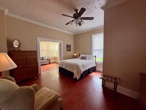 Une chambre à coucher avec un lit, une commode, une chaise et un ventilateur de plafond.