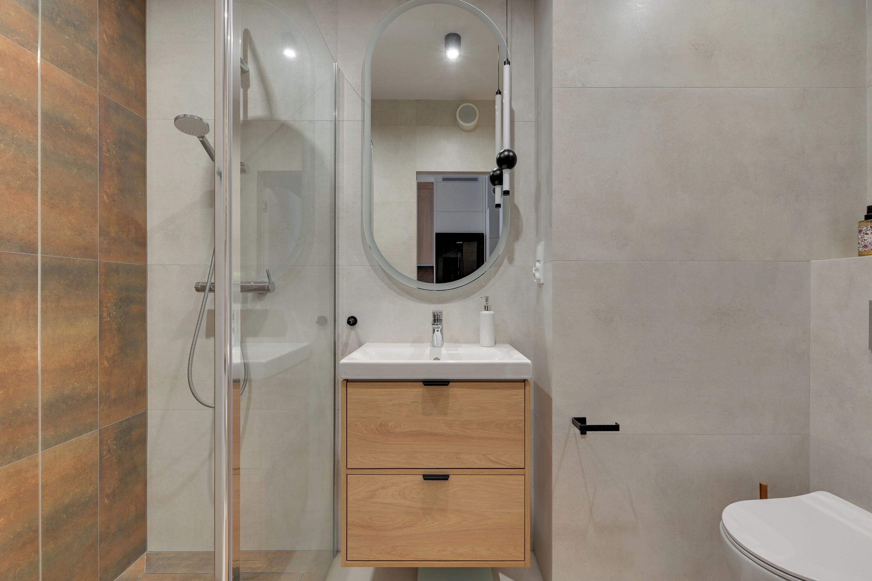 A bathroom with a shower, sink, mirror, and toilet.