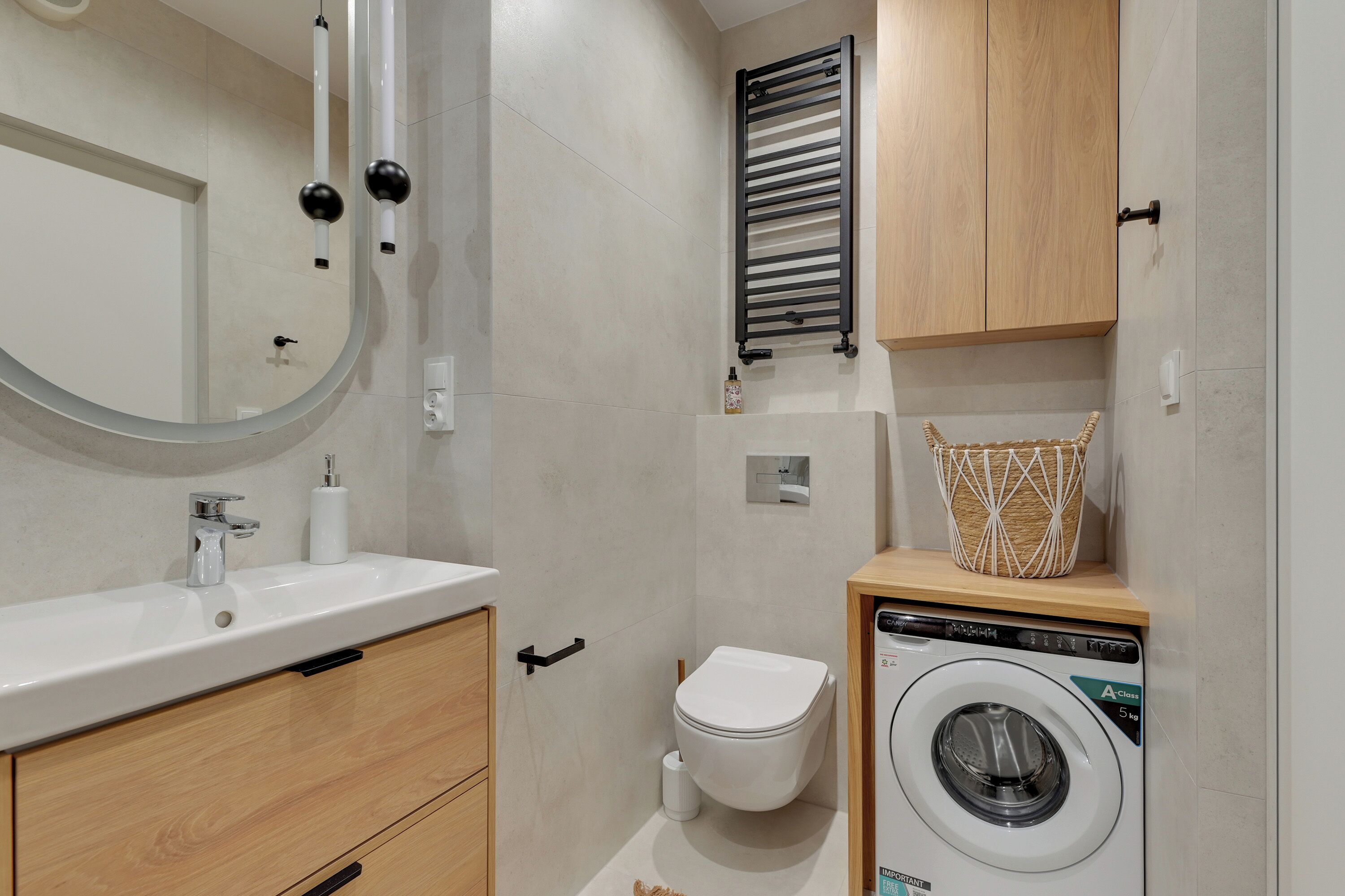 A compact bathroom with a sink, mirror, toilet, and a washing machine.