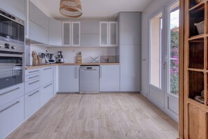 Une cuisine moderne avec des meubles blancs, un lave-vaisselle et un plan de travail en bois.