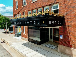 Un edificio de ladrillo con una entrada estilo cartel que dice 'Eugene Hotel'.