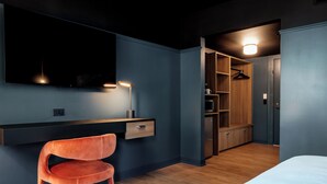 A modern bedroom with a bed, a desk, a chair, and a walk-in closet. - Eugene Hotel (Monroe)
