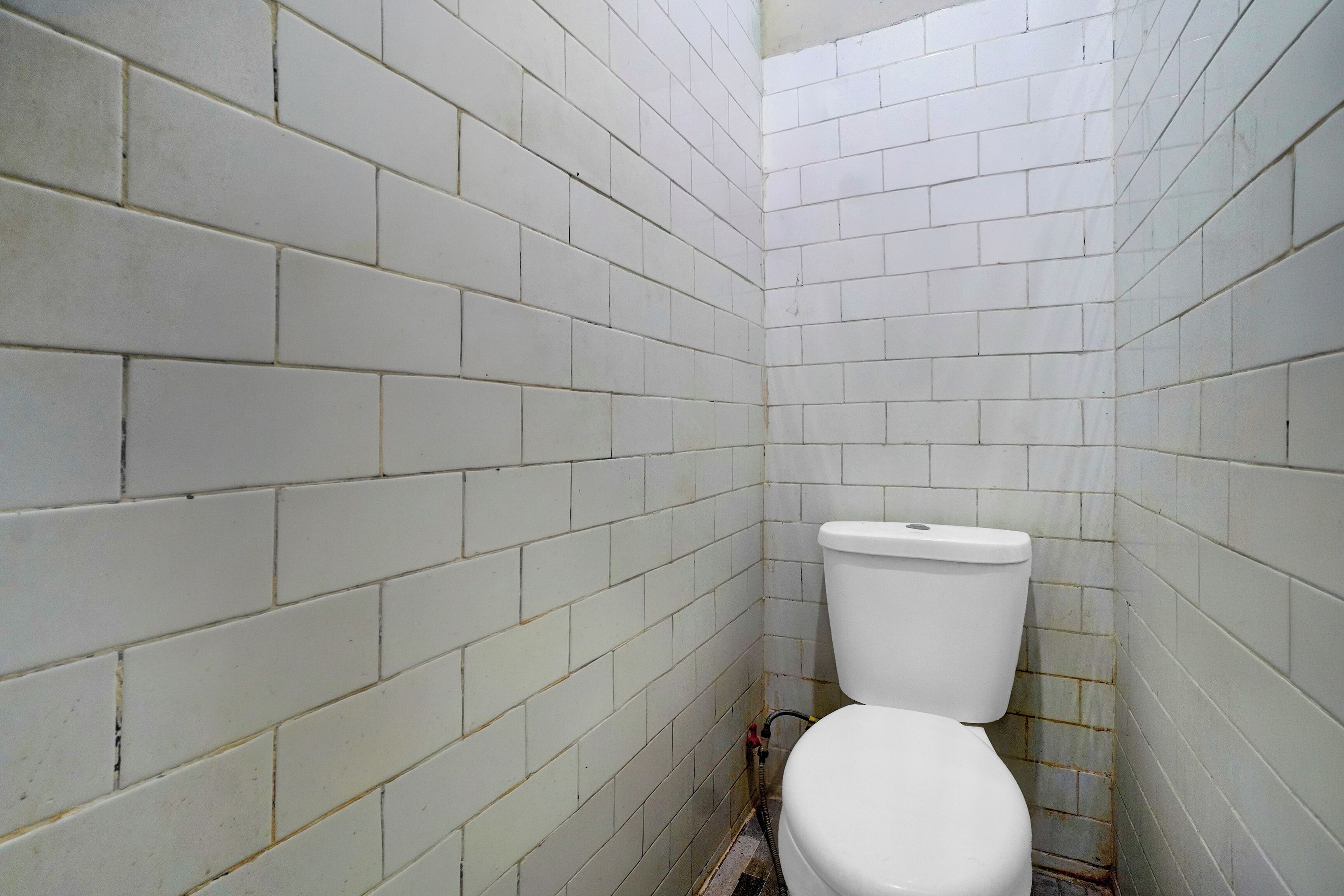 Un baño pequeño y estrecho con paredes de azulejos blancos y un inodoro blanco.