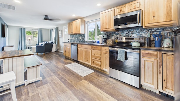 Una cocina moderna con armarios de madera, electrodomésticos de acero inoxidable y un ventanal grande.