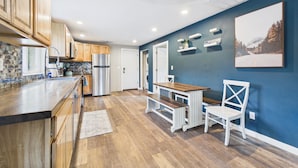 Una cocina moderna con armarios de madera, un refrigerador de acero inoxidable y un comedor con mesa y sillas.
