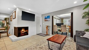 Uma sala de estar moderna com lareira, televisão de tela plana na parede, mesa de centro de madeira e sofá cinza.