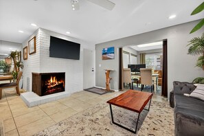 Ein Wohnzimmer mit Kamin, Flachbildfernseher, Sofa und Couchtisch.