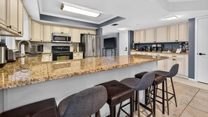 Uma cozinha moderna com bancadas de granito, eletrodomésticos de aço inoxidável e banquetas de bar.