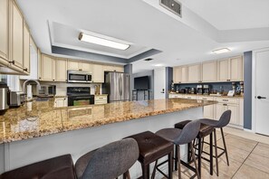 Eine moderne Küche mit Granit Arbeitsplatten, Edelstahlgeräten und Barhocker.