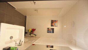 Ein Badezimmer mit einem weißen Waschbecken, einem Spiegel und zwei an der Wand hängenden Bildern.