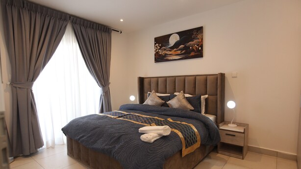 Ein Schlafzimmer mit einem großen Bett, einem Nachttisch mit Lampe und einem Gemälde an der Wand.