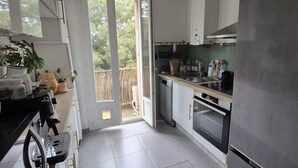 Cozinha moderna com uma geladeira grande, lava-louças e fogão. Há uma janela que traz luz natural e vista para o exterior.
