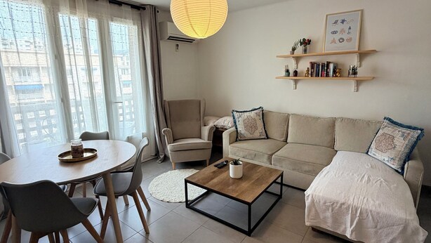 Uma sala de estar moderna com uma mesa de jantar redonda, um sofá, uma mesa de centro e um lustre.