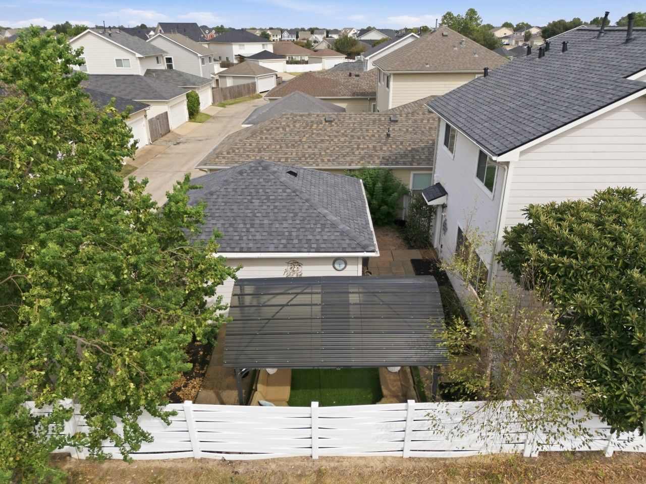 A residential area with multiple houses, a fenced yard, and a small garden.