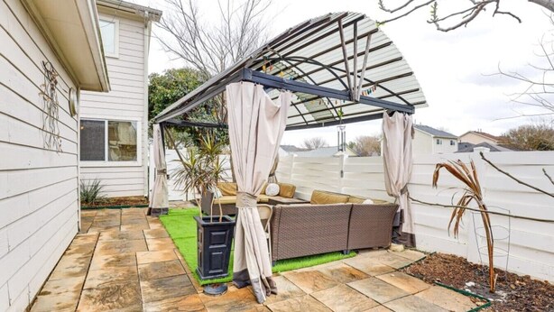 Un patio couvert aménagé avec des sièges, une pergola et un petit jardin.