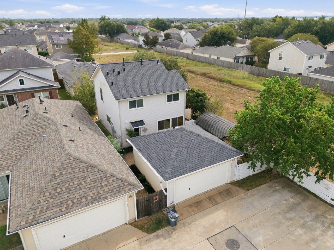 Zona residencial con casas, un patio cercado y un árbol.